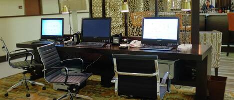 Une salle de conférence équipée de trois bureaux, chacun doté d’un ordinateur, de deux chaises de bureau et d’un tapis à motifs.