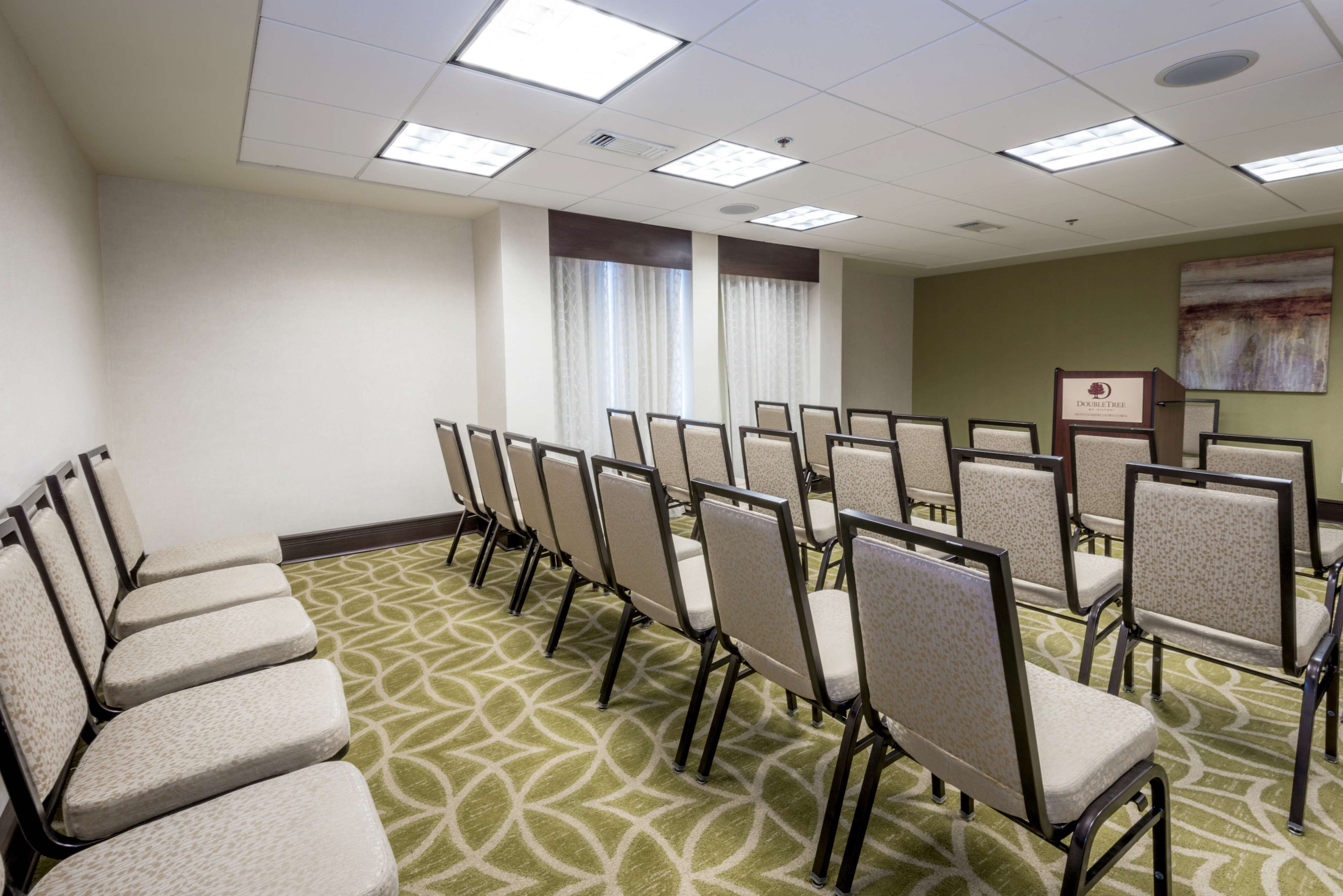 A conference room with rows of chairs, a podium, and a patterned carpet.