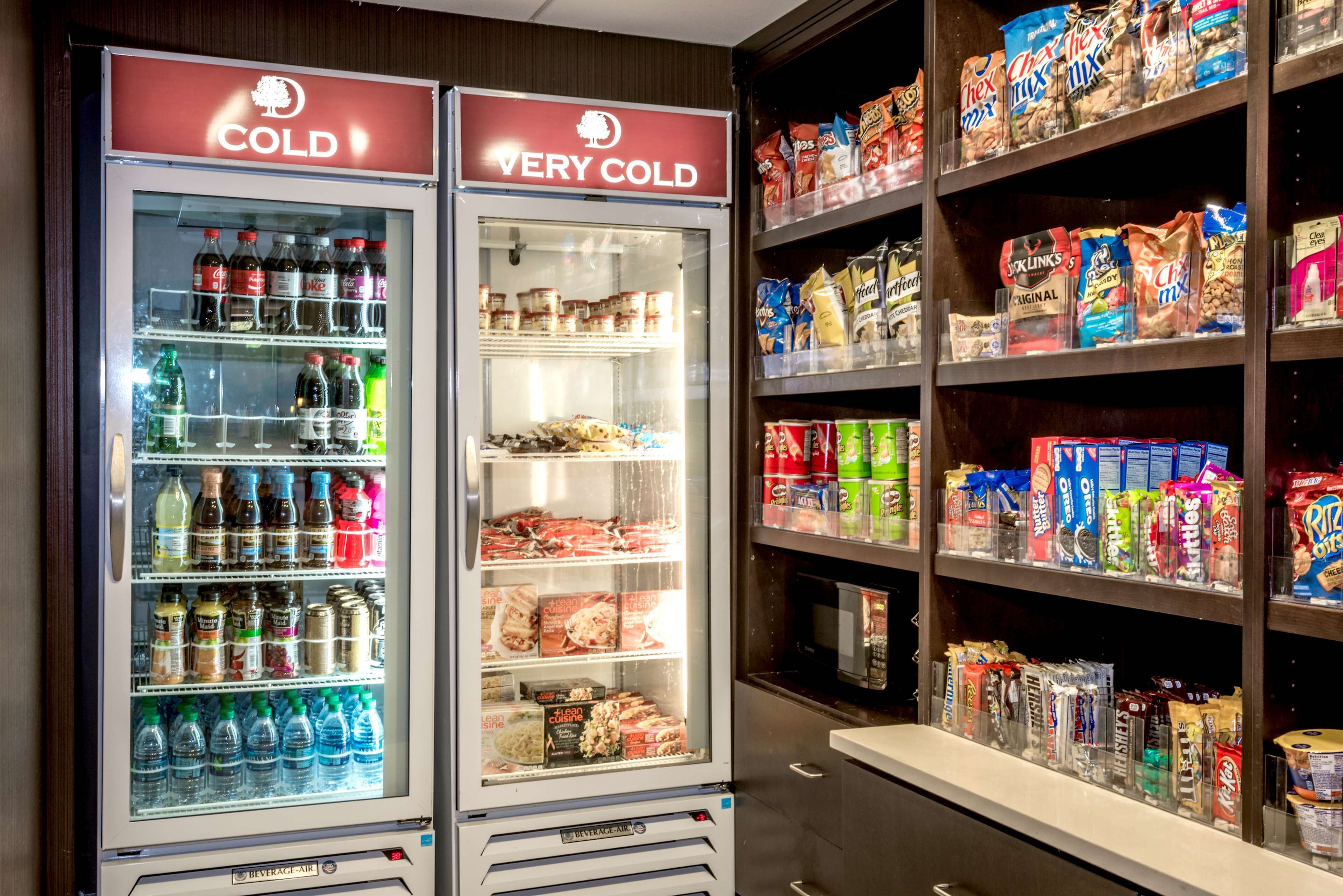 Dois dispensadores de bebidas com a inscrição 'FRIO' e 'MUITO FRIO', exibindo diversas bebidas e lanches.