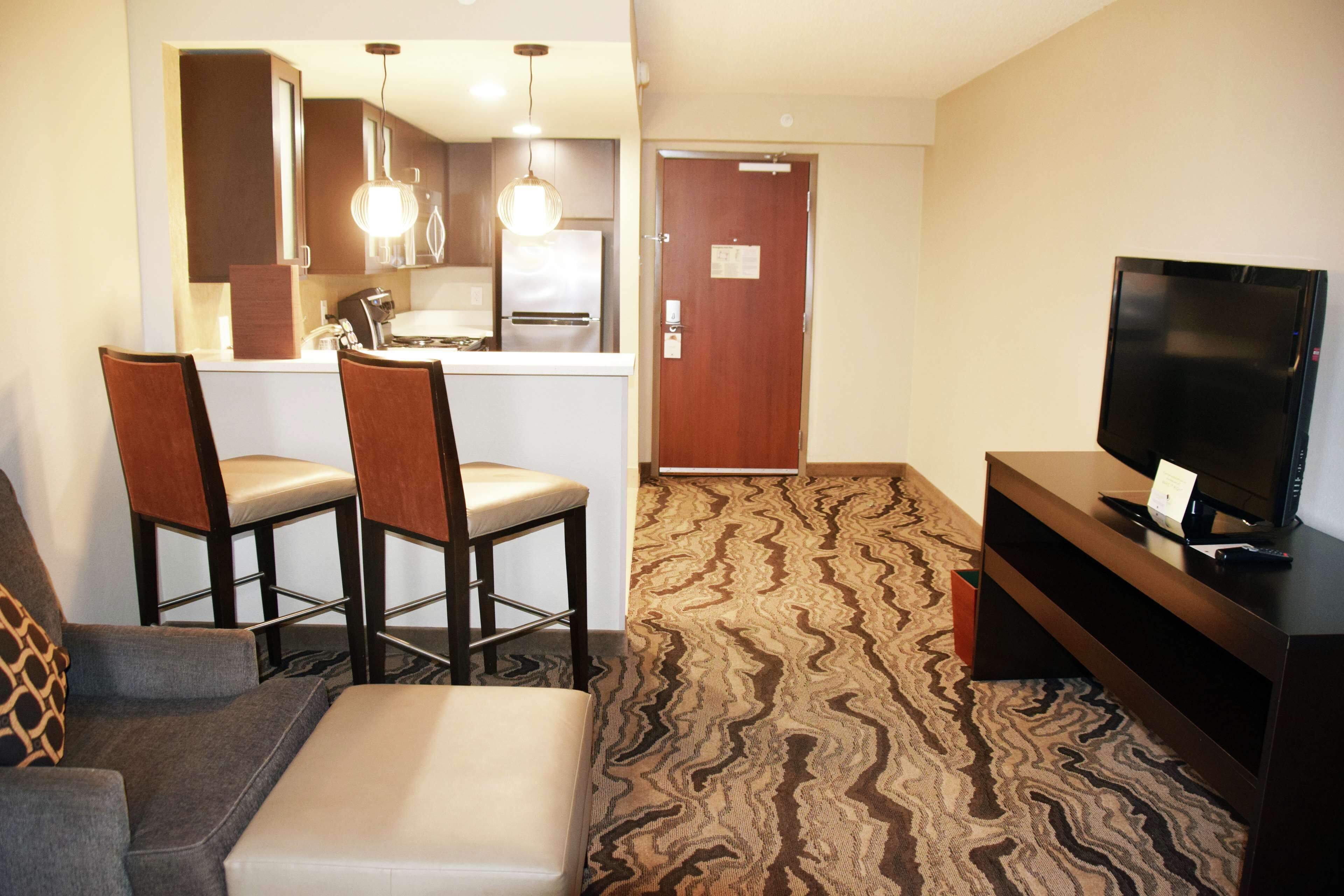 A compact living space with a kitchenette, a television, and a patterned carpet.