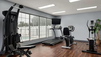 A gym with a treadmill, weight machines, and a bench.