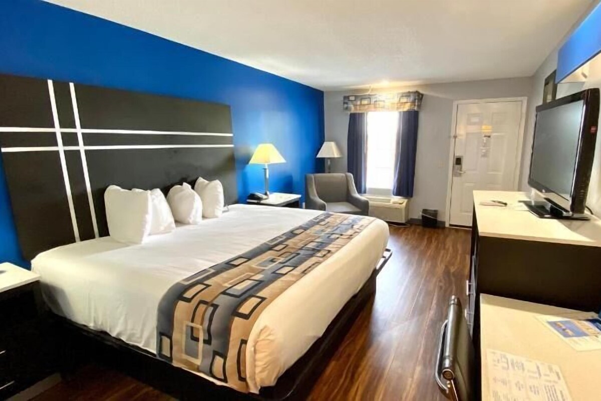 Une chambre d’hôtel avec un lit, un bureau avec un ordinateur, une télévision et une chaise.