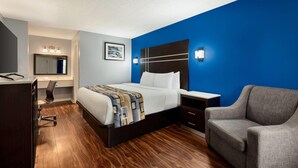 A hotel room with a bed, desk, chair, and a blue accent wall. - Baymont by Wyndham Albany at Albany Mall (Albany)