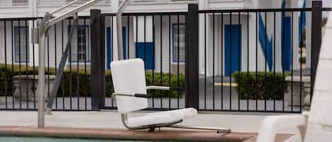 Een buitenzwembad, ligstoelen bij het zwembad