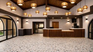 A reception area with a wooden reception desk, multiple pendant lights, and a speckled floor. - Hotel Embarque, Unscripted By Hyatt (Phoenix)