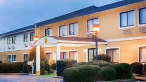 A hotel with a yellow facade, multiple windows, and a covered entrance area.
