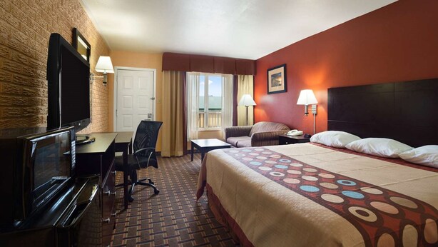A hotel room with a bed, a desk with a TV, a chair, a lamp, and a window with curtains. - FairBridge Inn Express Stuttgart (Stuttgart)