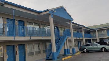 A multi-story motel with blue railings and a parking lot.