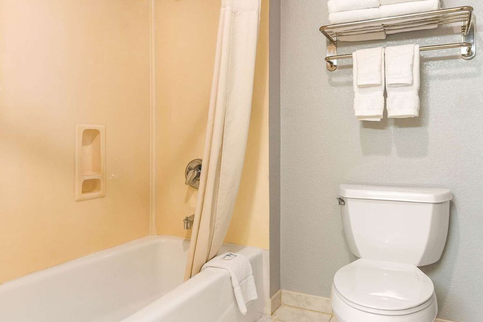 A bathroom with a bathtub, toilet, and towel rack.