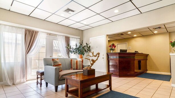 A hotel lobby with a sofa, armchair, wooden coffee table, and a reception desk. - Auburn House Hotel (Auburn)