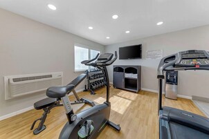Une salle de sport équipée de matériel d’exercice, d’un téléviseur et d’un distributeur d’eau.