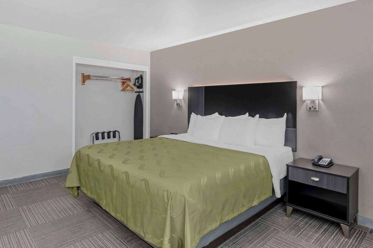 Ein Hotelzimmer mit Bett, Nachttisch und Kleiderhaken.