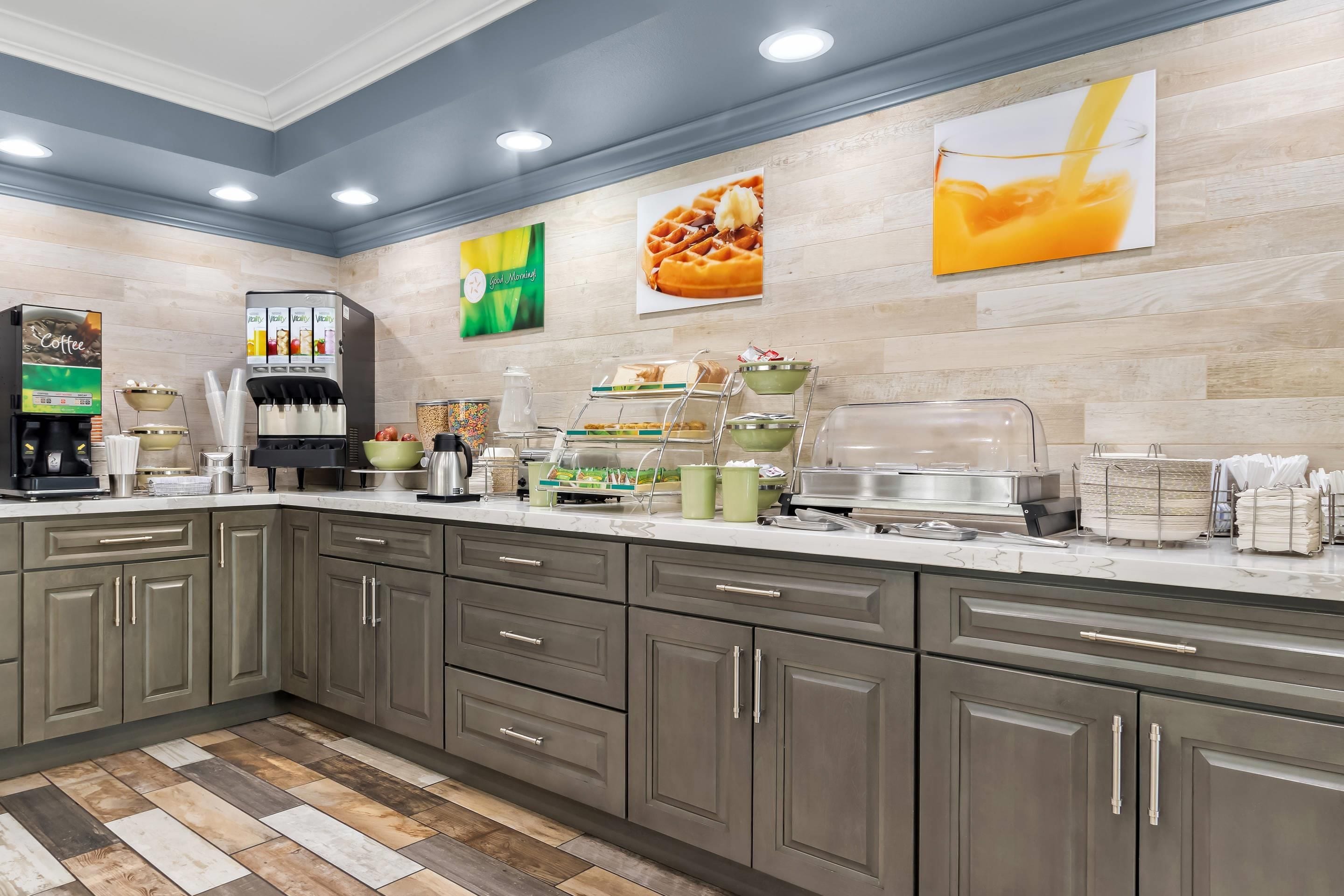 A modern kitchen with a marble countertop, stainless steel appliances, and a variety of food and drink dispensers.