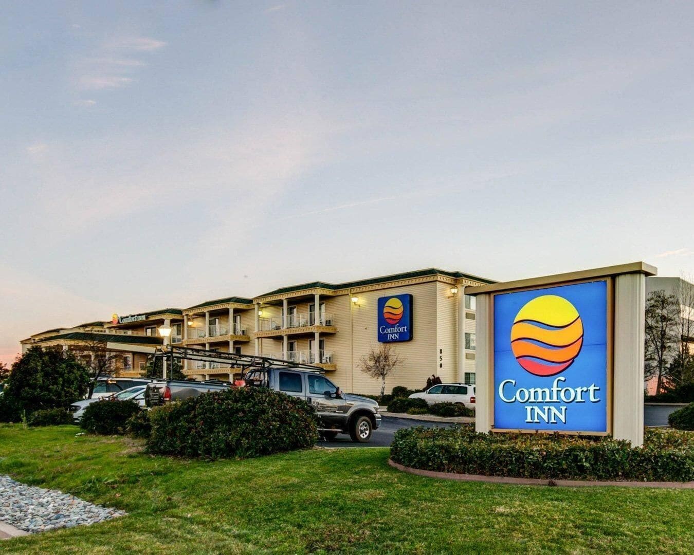 A Comfort Inn hotel with a large sign, multiple balconies, and a parking lot.
