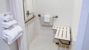 A shower with a handheld showerhead, a towel rack with folded towels, and a grab bar.