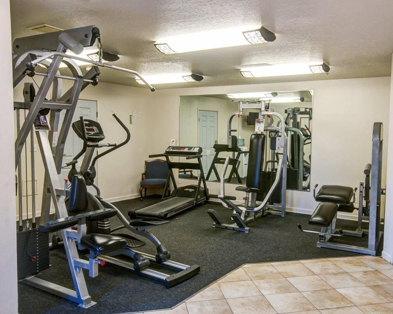 Un gimnasio con cintas de correr, elípticas y equipo de levantamiento de pesas.