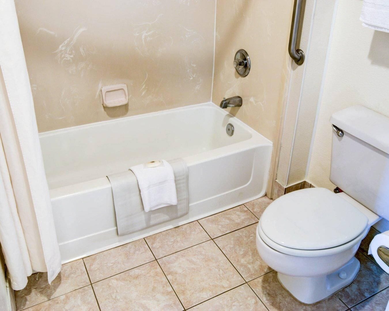 A bathroom with a bathtub, toilet, and a towel rack.