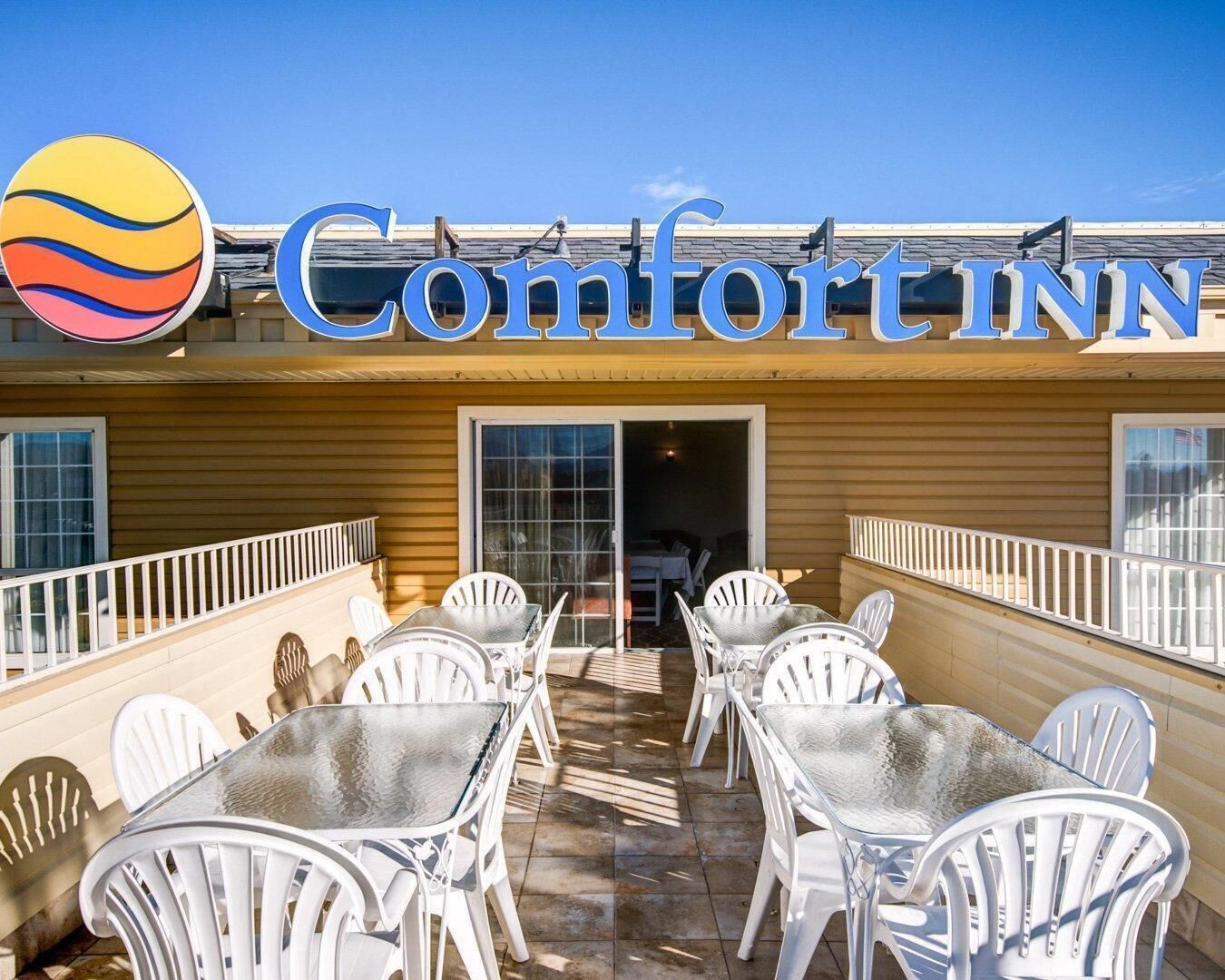A Comfort Inn with outdoor seating and a clear sky.