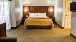 Una habitación de hotel con una cama grande, dos mesitas de noche, un televisor y una ventana con cortinas.