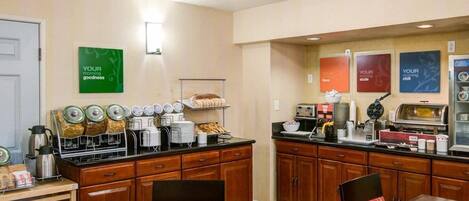 Una cocina de hotel con una barra de buffet, que incluye una estación de café y diferentes alimentos.