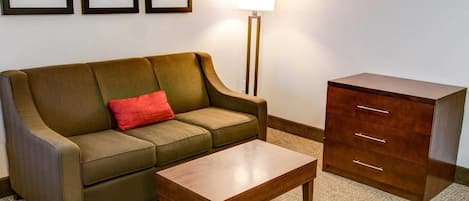 Ein Zimmer mit einer Couch, einem Holztisch, einer Kommode und drei gerahmten Bildern an der Wand.