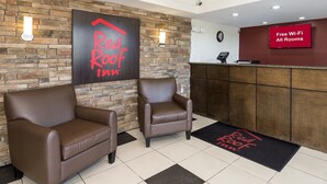 En reception på Red Roof Inn med två läderfåtöljer, en receptionsdisk och en skylt som visar att det finns gratis Wi-Fi i alla rum.