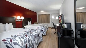 Ett hotellrum med en säng, sänglampor, ett skrivbord med en dator och en tv.