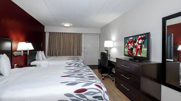 A hotel room with a large bed, a desk, a television, and a mirror.