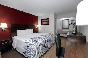 A hotel room with a bed, bedside lamps, a desk with a mirror, and a picture on the wall. - Red Roof Inn Bloomington - Normal/ University (Bloomington)