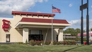 A Red Roof Inn with a flagpole, a clear sky, and a red roof. - Red Roof Inn Bloomington - Normal/ University (Bloomington)