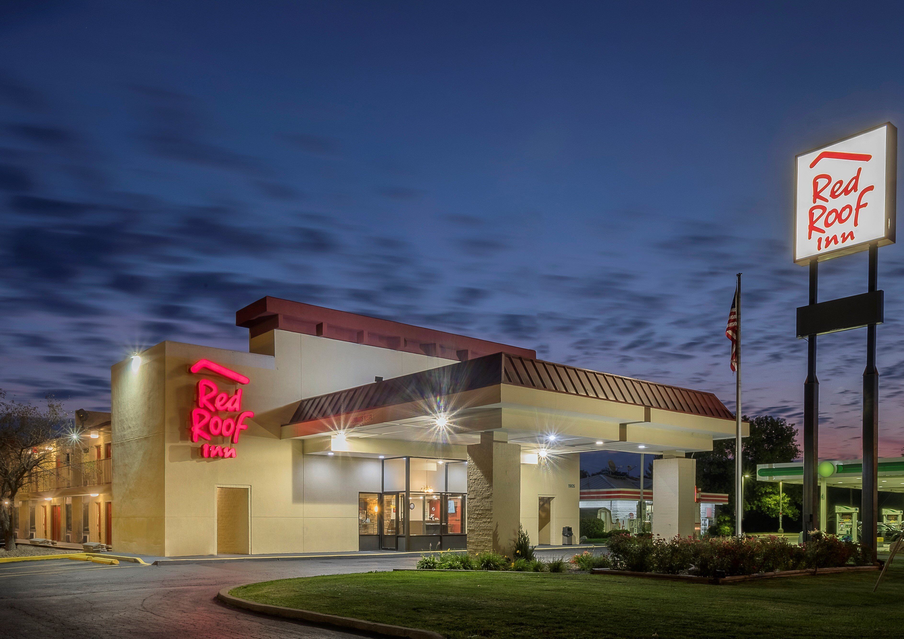 A Red Roof Inn with a modern design, featuring a prominent neon sign and a well-lit entrance.