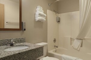 Un baño con lavamanos de granito, inodoro, bañera y ducha.