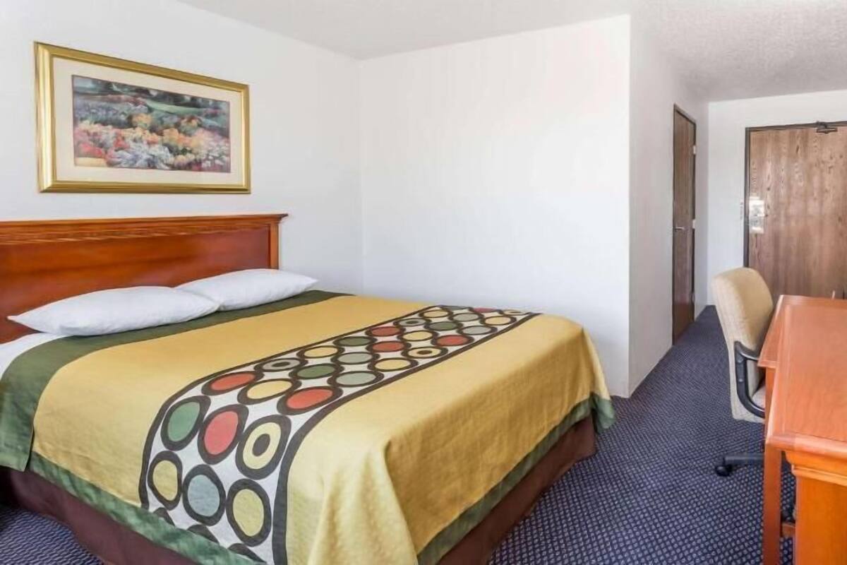 A hotel room with a bed, a television, a desk, and a door.