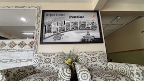 A framed welcome sign for Pontiac, Michigan, featuring a cityscape and the state capitol building.