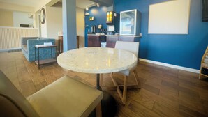 Een moderne woonkamer met een ronde tafel, zitplaatsen en een keuken in de achtergrond.