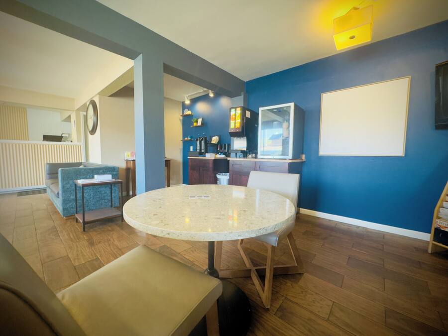 A modern living room with a round table, seating, and a kitchen area in the background.