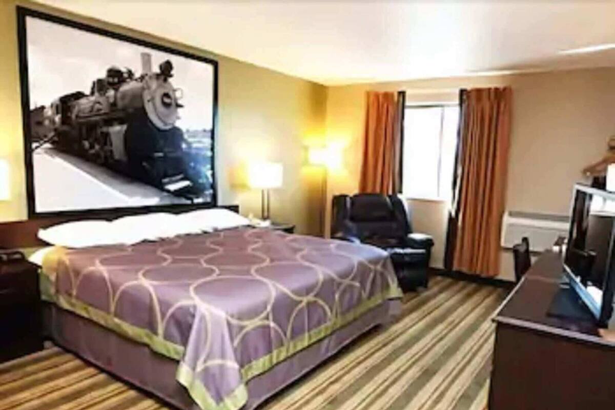 Una habitación de hotel con una cama grande, un escritorio con ordenador, una silla y un televisor.