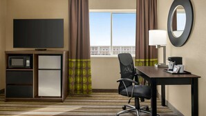 A hotel room with a flat-screen TV, a desk with a lamp, a chair, a minibar, and a window with curtains. - Super 8 by Wyndham Liberal KS (Liberal)