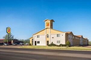 Un motel Super 8 con una torre central, varias habitaciones y un estacionamiento.