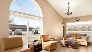 A spacious living room with a large arched window, a chandelier, and a view of a parking lot. - Super 8 by Wyndham Liberal KS (Liberal)