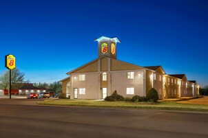 Un hotel con un llamativo letrero de 'Super 8', una torre central iluminada y una fachada bien iluminada.