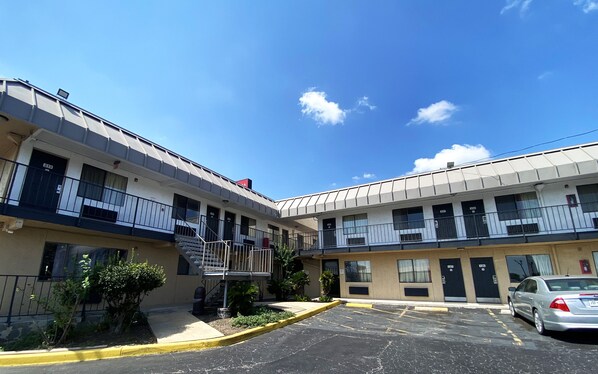 A two-story motel with a parking lot and a clear blue sky.