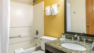 Un baño con bañera, inodoro, lavamanos y espejo.
