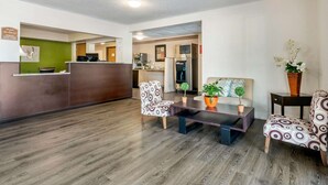 A reception area with a wooden reception desk, patterned chairs, a coffee table, and a potted plant. - Quality Inn & Suites Leesburg Chain of Lakes (Leesburg)