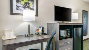 Une chambre d’hôtel équipée d’un bureau, de deux lampes, d’une télévision, d’un four à micro-ondes et d’un réfrigérateur.