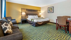 A hotel room with a bed, a sofa, a dining table, and a chair. - Quality Inn & Suites Leesburg Chain of Lakes (Leesburg)
