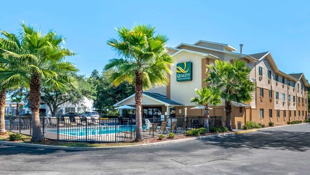 A hotel with a pool, palm trees, and a sign reading "Quality Inn & Suites". - Quality Inn & Suites Leesburg Chain of Lakes (Leesburg)