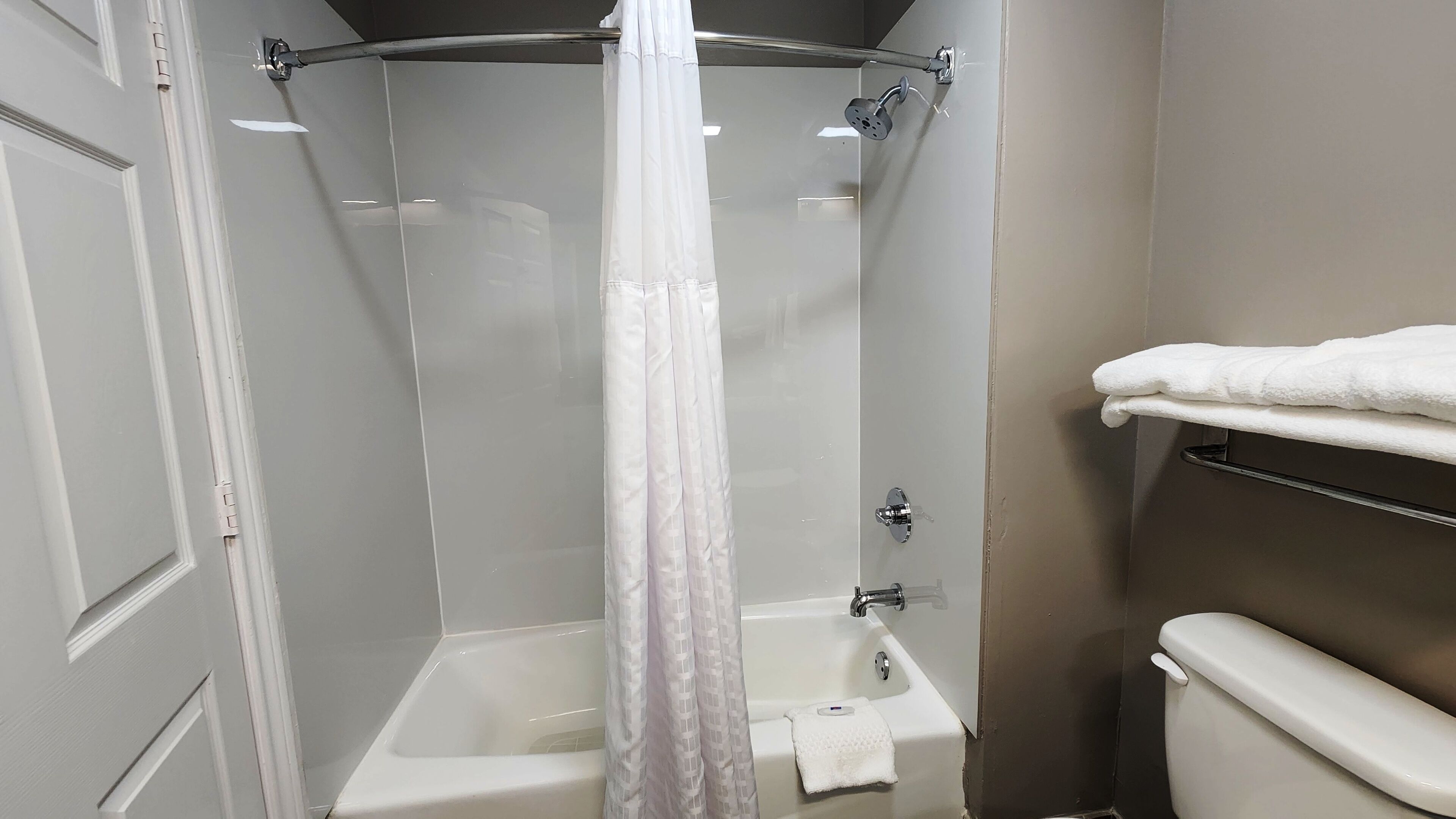 A bathroom with a shower, toilet, and towel rack.