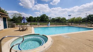 A swimming pool with a hot tub, lounge chairs, and a fenced area with a playground. - Motel 6 Ennis, TX (Ennis)