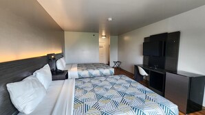 A hotel room with two beds, a desk, a TV, and a door leading to a bathroom. - Motel 6 Ennis, TX (Ennis)